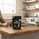 shopnathans.com Pure Infinity Botanicals Green Maeng Da kratom capsules in a black pouch on a wooden kitchen table.