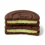 shopnathans.com Oreo soft chocolate cake with creamy pistachio filling stacked in two halves on a white background