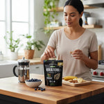 A woman at a kitchen counter taking a shopnathans.com Pure Infinity Botanicals Trainwreck Kratom capsule with water.